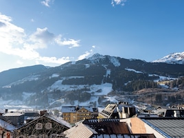Eine Bergstadt mit schneebedeckten Gipfeln, einer Skipiste und Häusern mit schrägen Dächern.