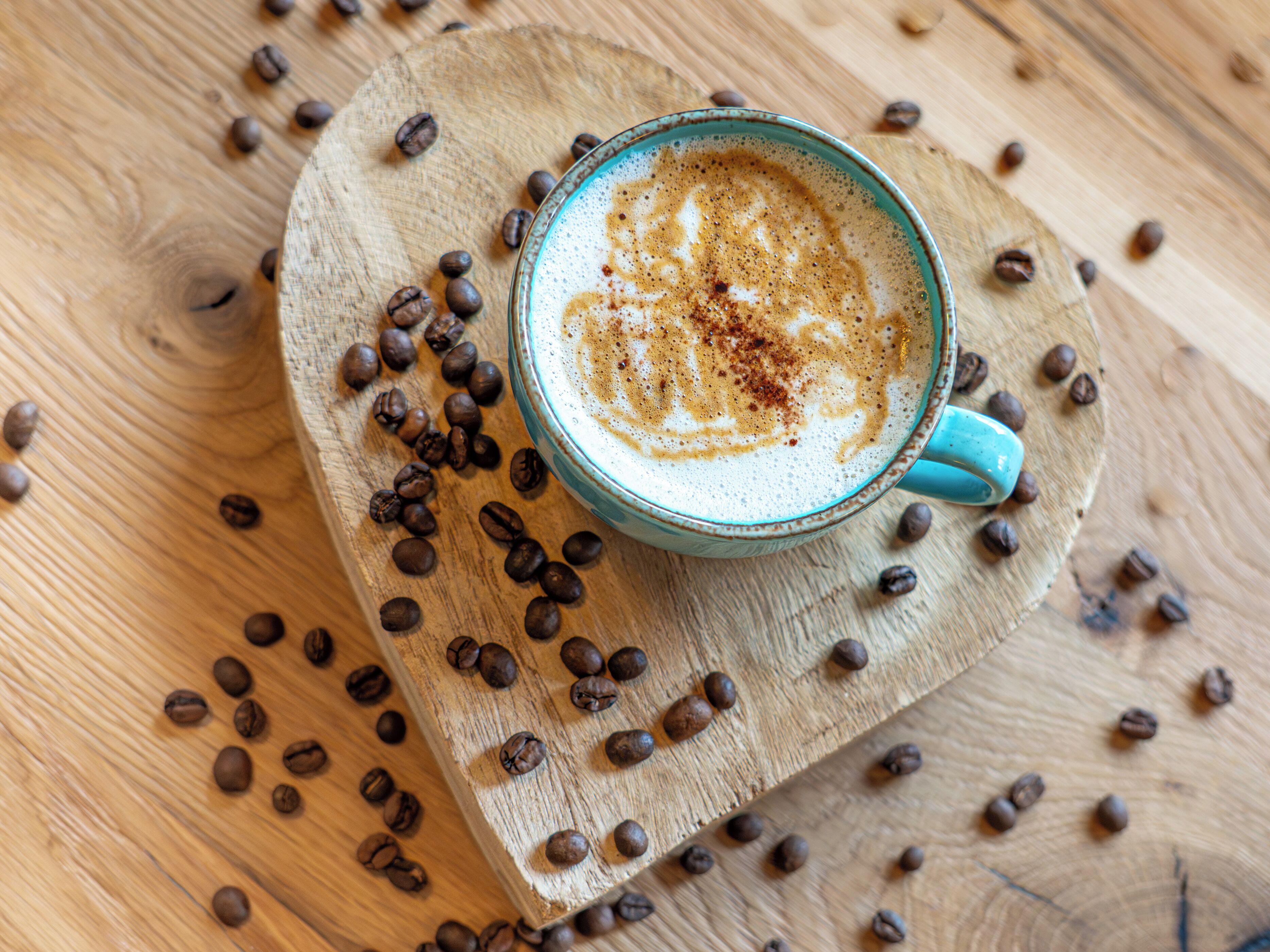 Une tasse de café posée sur une planche en bois, entourée de grains de café.