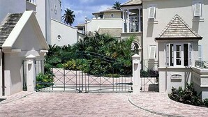 Zona residencial con entrada protegida, caminos pavimentados y edificios con balcones y detalles decorativos.