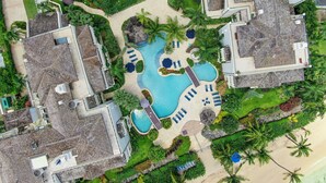 Vista aérea de un resort con varias edificaciones, una piscina central y abundante vegetación circundante.