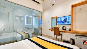 Habitació d'hotel amb llit, escriptori, cadira, televisió i petita cuina.