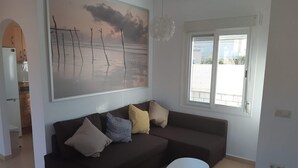 En stue med en mørkebrun sofa, et hvidt sofabord og et stort abstrakt billede på væggen.