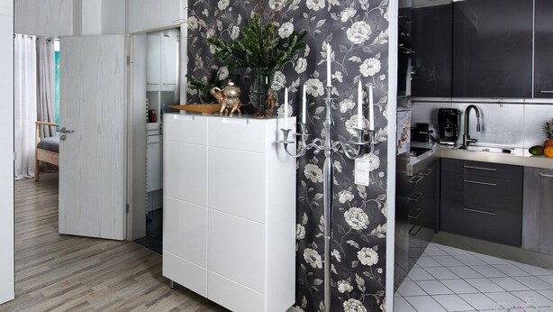 A modern kitchen with white cabinets, a black floral backsplash, and a white tiled floor. - Lo Exclusive Stuttgart - Cozy and central apartment with garden (Stuttgart)