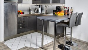 A modern kitchen with stainless steel appliances, a bar area with stools, and a fruit bowl on the counter. - Lo Exclusive Stuttgart - Cozy and central apartment with garden (Stuttgart)