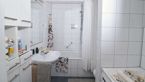 A small, clean bathroom with white tiles, a sink, a shower, and a toilet. - Lo Exclusive Stuttgart - Cozy and central apartment with garden (Stuttgart)