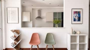 A modern interior with two chairs, a bookshelf, and a white cabinet.