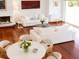 Una sala de estar moderna con un sofá blanco, una mesa de centro y un comedor con una mesa redonda y sillas.