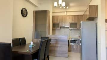 A modern kitchen with wooden cabinets, a built-in microwave, and a refrigerator.