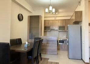 Une cuisine moderne avec des meubles en bois, un four à micro-ondes encastré et un réfrigérateur.