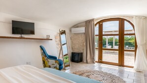 A bedroom with a TV, a chair, a bed, a mirror, and a view of the outside. - Hasamami Luxury Villa in Ostuni, 4 double bedrooms, private pool  (Ostuni)