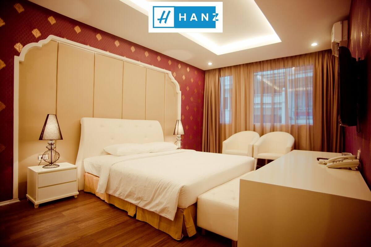 A hotel room with a large bed, a desk, a chair, and a nightstand.