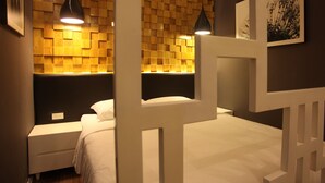 A bedroom with a wooden headboard, a white bedside table, and a wall-mounted light fixture.