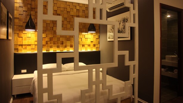 A modern bedroom with a geometric-patterned headboard, a white bed, and a nightstand.