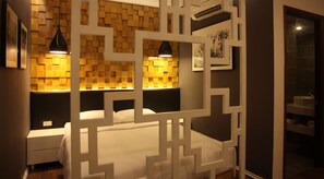 A modern bedroom with a geometric-patterned headboard, a white bed, and a nightstand. - HANZ Friday Royal Hotel (Ho Chi Minh City)