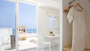 A balcony with a view of the sea, a dining area with a table and chairs, and a clothing rack with a white dress. - BJ Cala Morlanda Estudios (Manacor)