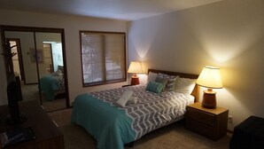 Ein Schlafzimmer mit einem Bett, zwei Nachttischlampen, einem Spiegel und einer Kommode.
