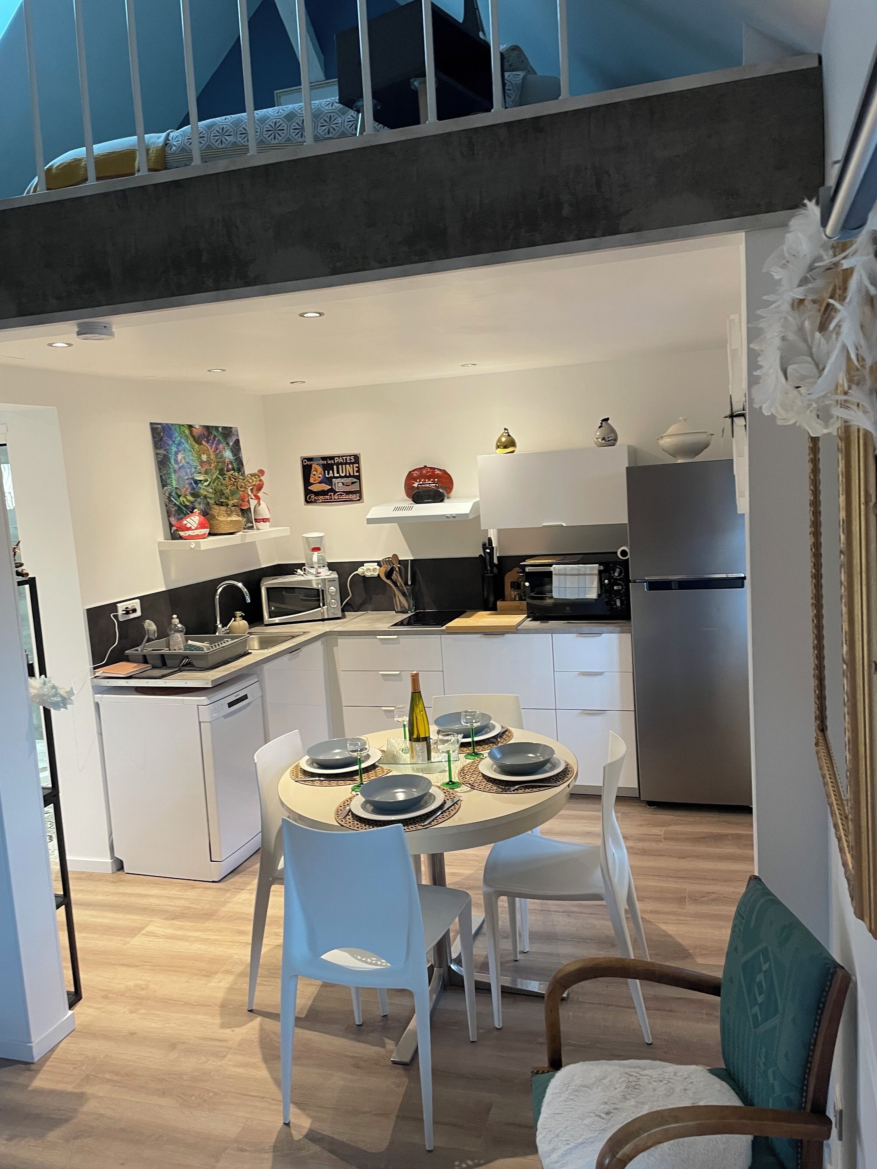 A modern kitchen with white cabinetry, a dining area with a round table, and a staircase leading to an upper level.