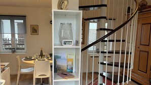 A modern kitchen with a dining area, a spiral staircase, and a bookshelf. - Maisonnette (Wintzenheim)