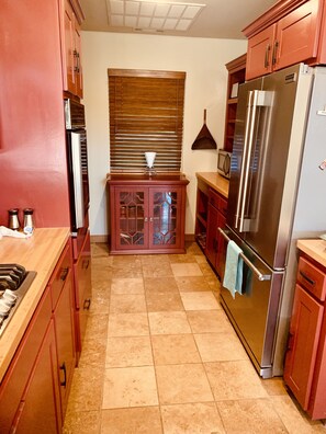 A kitchen with red cabinets, a stainless steel refrigerator, and a window with blinds. - Lakeside house with fireplace, deck, and a fenced backyard with firepit. (Springdale)