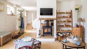 Een gezellige woonkamer met een open haard, een televisie erboven en een houten plank met decoratieve objecten.