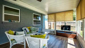 A covered outdoor seating area with wicker furniture, a television, and a window with the word "Beach" on it. - Sweet Home Ponte Verdra: TPC Golf+Park+Outdoor Fireplace+ Nearby Beach Access！ (Ponte Vedra Beach)