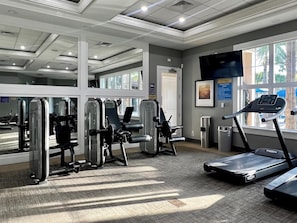A gym with exercise equipment, a treadmill, and large windows.