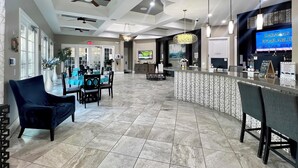 A spacious lobby with a reception desk, seating area, and a television displaying 'CABANAS AVAILABLE.'