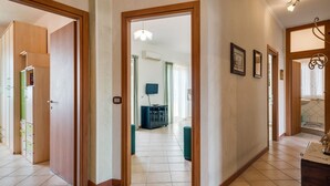 A hallway with wooden doors, a tiled floor, and a dining area with a table and chairs. - GuestHost - Roomy and Bright Apartment with Balconies x6 (Catania)
