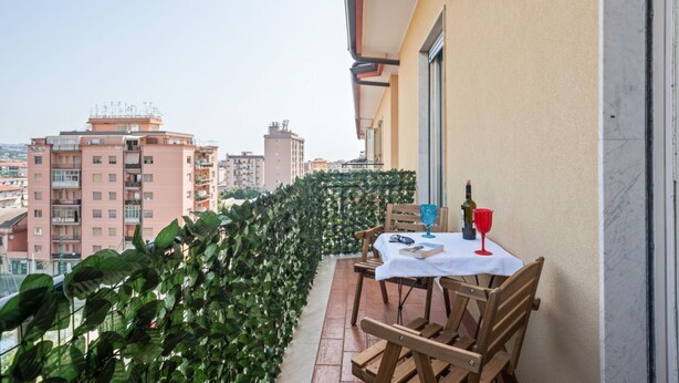 A balcony with a table set for two, a bottle of wine, and a glass. - GuestHost - Roomy and Bright Apartment with Balconies x6 (Catania)