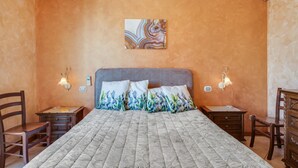 A bedroom with a bed, two bedside tables, a wall-mounted air conditioner, and a wall art piece. - GuestHost - Roomy and Bright Apartment with Balconies x6 (Catania)