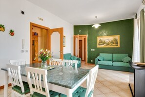 Un área de comedor con una mesa y sillas, un sofá verde y un cuadro en la pared.