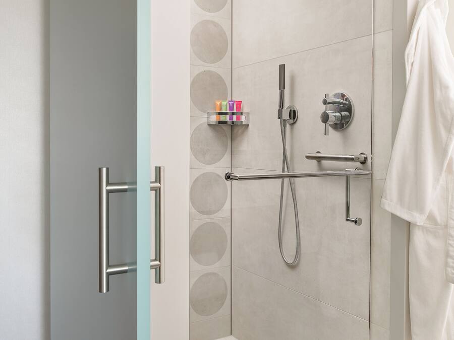 Un espace douche moderne doté d’un pommeau de douche à main, d’un flexible de douche et d’une cabine de douche en verre.
