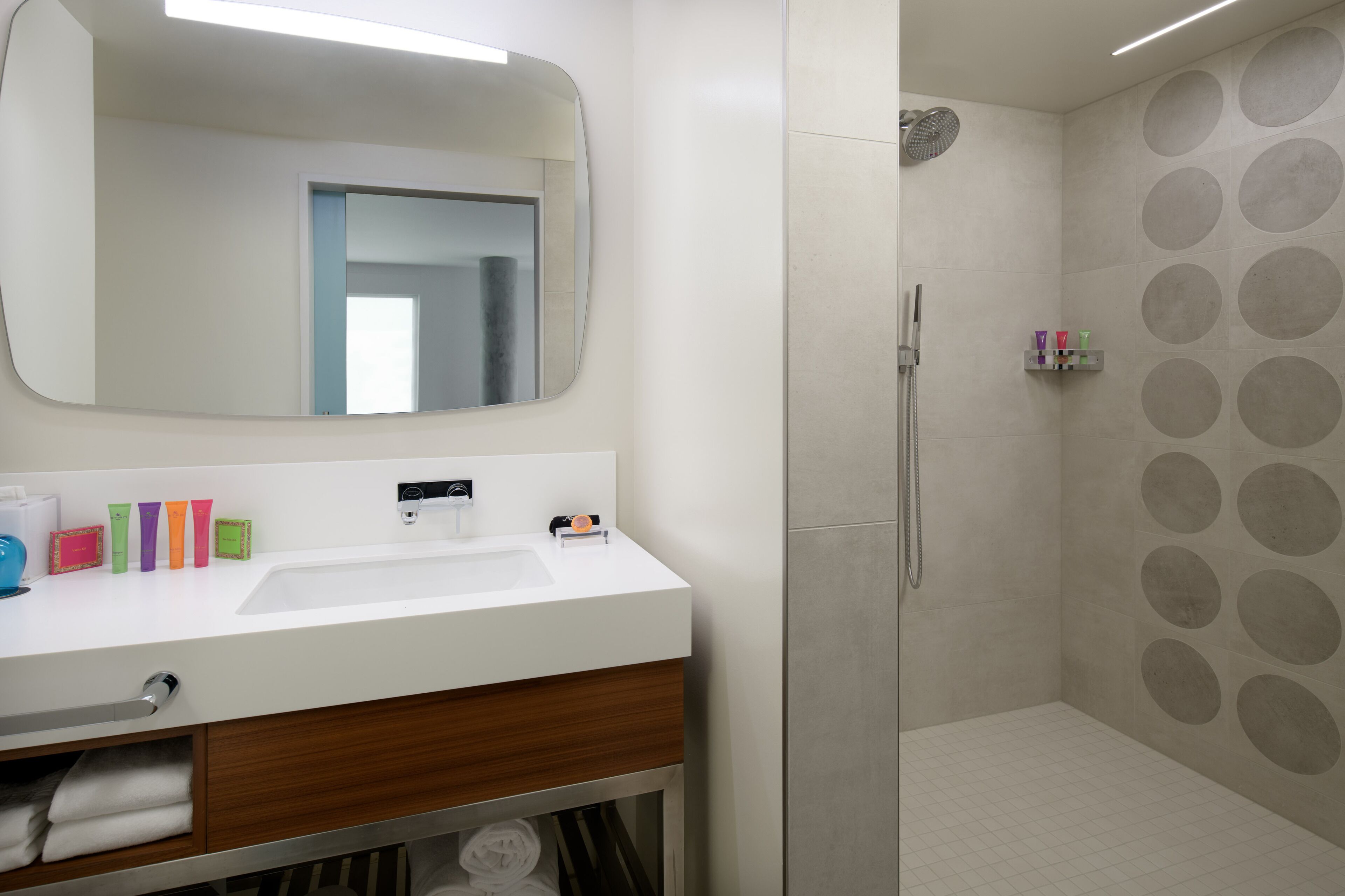 A bathroom with a white sink, a mirror, and a shower with circular patterns on the wall.