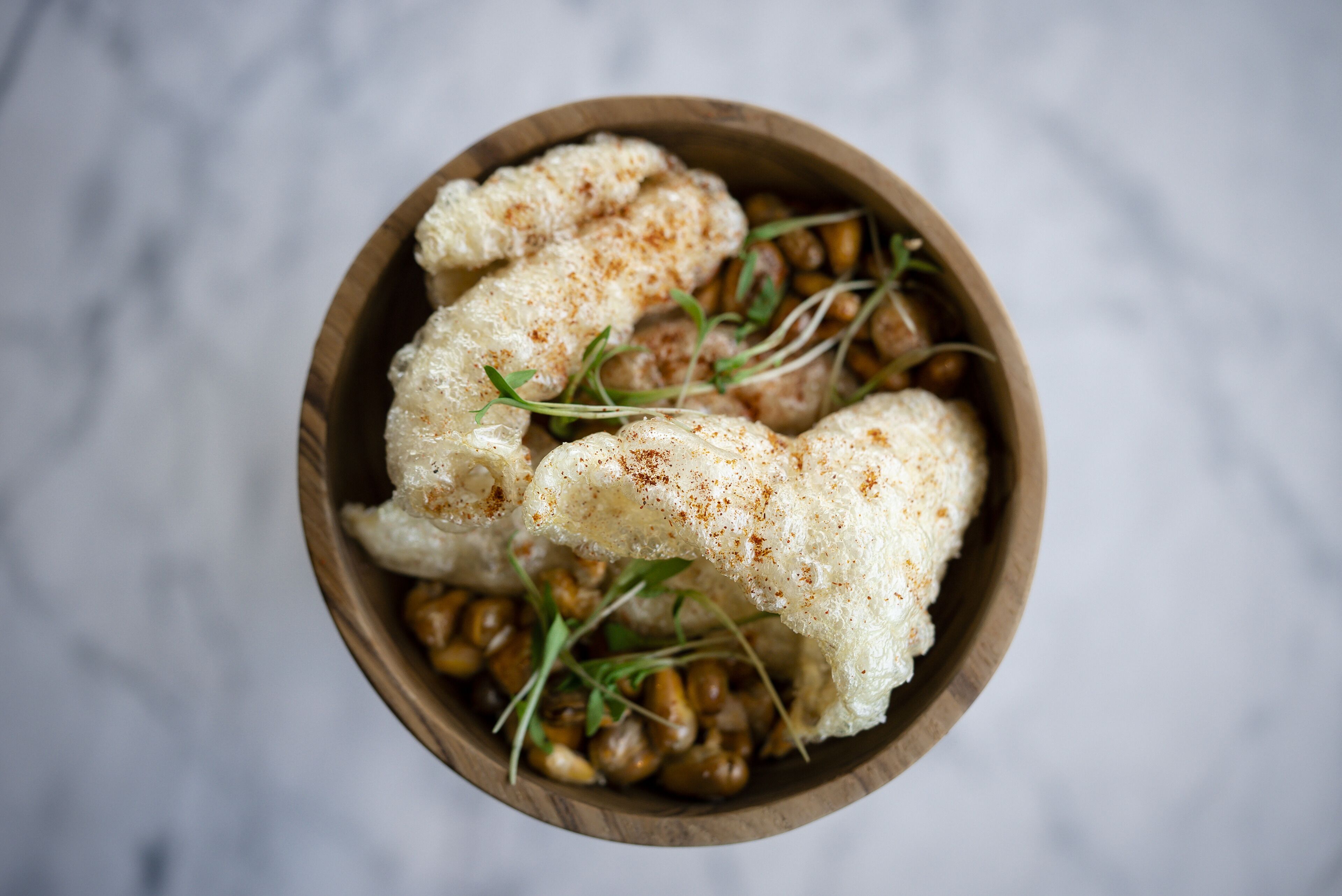 A wooden bowl containing cauliflower and sprouts.