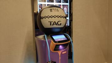 A fitness machine with a digital screen and a ball at the top, located in a hotel lobby.