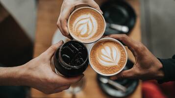 Three cups of coffee with latte art, held by hands.