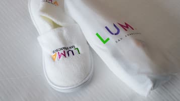 A pair of white slippers with embroidered text and a white towel with similar text.