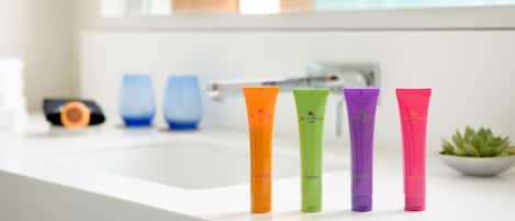 Quatre tubes de shampoing aux couleurs vives sont posés sur le comptoir d’une salle de bain.