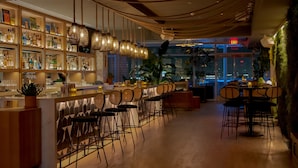 Eine Bar mit einer langen Theke, verschiedenen Sitzgelegenheiten und Blick auf die Stadt.