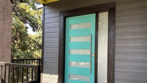 A modern house with a teal front door, a small porch with a black railing, and a wooden exterior. - Beautiful New Luxury Home - Close to The Village - Amazing Ski In/Out too. (Silver Star Mountain)