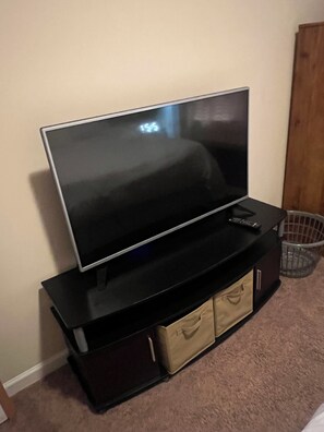 A flat-screen TV on a black entertainment unit with storage drawers.