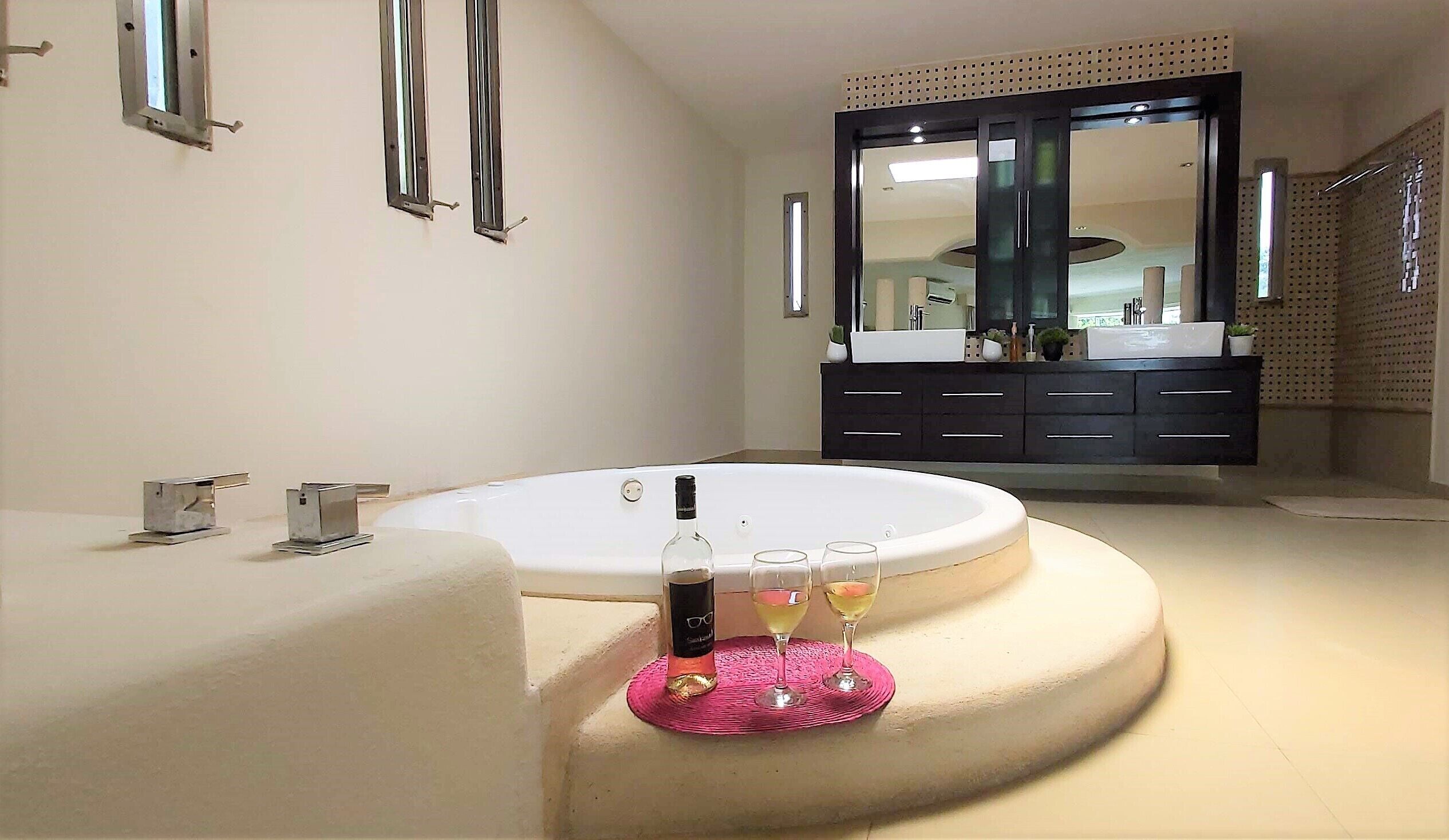 Une salle de bain moderne avec une baignoire sur pieds, un grand miroir et un meuble-lavabo foncé.