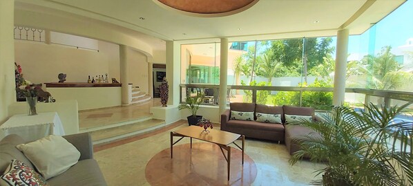 A spacious living area with a sofa, coffee table, and a balcony with a view of greenery.