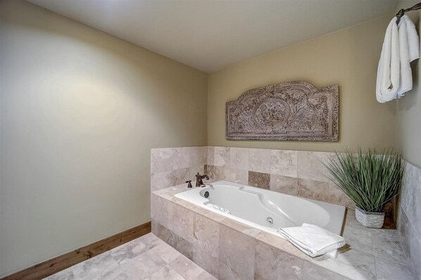 Un baño moderno con una bañera independiente, una pieza decorativa sobre la bañera y una planta en maceta a un lado.
