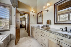 Une salle de bain spacieuse avec un grand meuble-lavabo, une baignoire et une douche à l’italienne.