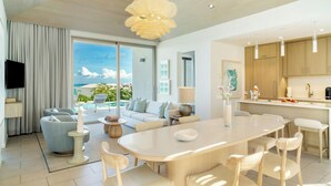 A modern living room with a large window, a dining area, and a kitchen. - Rock House (Providenciales)