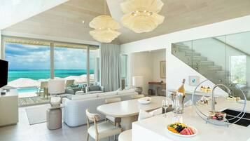 Un hotel moderno con una habitación amplia y ventana con vista al océano, una zona de comedor y una escalera.