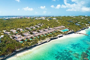 An aerial view of a resort with multiple buildings, a beach, and clear turquoise waters. - Rock House (Providenciales)