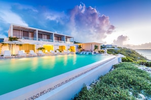 A modern hotel with a pool, lounge chairs, and a view of the sea. - Rock House (Providenciales)