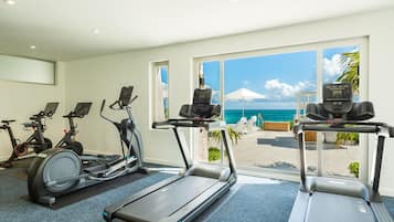 A gym with treadmills, stationary bikes, and a view of the ocean.